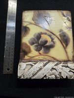 Front of tile beside ruler indicating approx 6 x 8 inches, showing full floral design and border