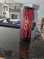 Lamp lit showing tree silhouette design and cord