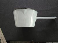 side view of white enamel saucepan showing body and handle