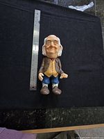Full view of Benjamin Franklin coin bank next to ruler