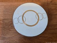 Top view of compact showing white enamel lid and gold ring motif