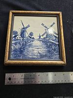 Front view of framed Delft tile with ruler for scale