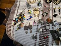 Overview of left section showing colourful bead earring, rhinestone hoops, owl brooch and assorted small earrings