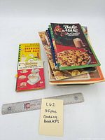 Stack of assorted cookery booklets with ruler for scale, top booklet Bake Make & Create for Christmas
