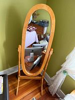Front view of freestanding oval mirror, room background