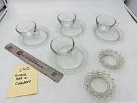 Entire lot showing four plates each with a cup and two coasters beside a ruler for scale