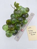 Top view of entire green glass grape cluster next to ruler