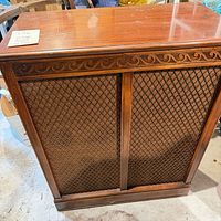 Closed wood console showing front lattice speaker panels and carved trim