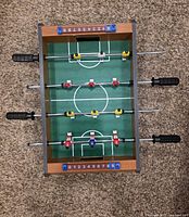 Top view of mini foosball table showing playfield, rods, players, score counters