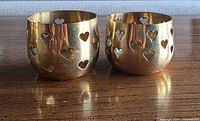 Pair of brass tealight holders with heart cutouts front view