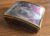 Closed trinket box showing angel lid art, purple glass sides, brass frame