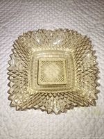 Top view of square amber pressed glass bowl showing hobnail diamond pattern and scalloped rim