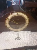 Front view of wooden mantel clock and winding key