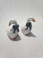 Front view of both ceramic geese shakers showing blue bows and orange beaks
