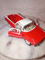 Front three-quarter view with driver door open showing red and white exterior and cream interior