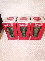 Front view of three boxed Coca-Cola green contour glasses