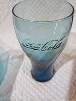Close-up of one blue teal Coca-Cola embossed glass