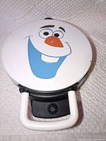 Closed waffle maker showing Olaf face graphic on lid
