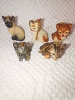 Group shot of five miniature cat ornaments showing size, colours and gold hang strings
