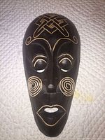 Front view of carved wood mask showing motifs and color