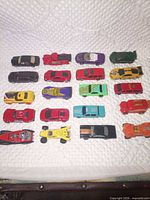 All 20 die-cast cars laid out in four rows on white quilted surface