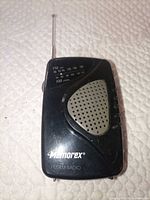 Front view of black Memorex FM/AM radio with antenna extended and speaker grille visible