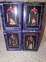 Front view of four boxed Animal Collect-A-Bell ornaments showing individual animal designs within bells