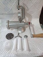 overall view of meat grinder with crank, clamp and accessories laid out