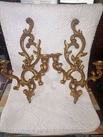 Full view of both matching gold Rococo style two-arm wall sconces on white background