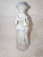 Front view of porcelain woman musician figurine showing lyre, dress details and hat