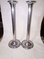 Full view of both silver-plated fluted candlesticks standing side by side