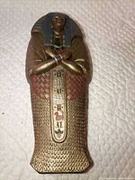 Front view of brass-tone metal sarcophagus figurine
