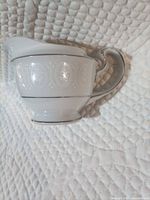 Left side view of porcelain creamer showing floral band and silver trim