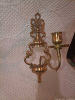 Full view of brass wall sconce showing backplate, arm and candle cup