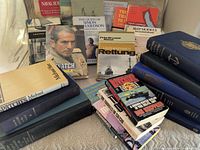Front view of assorted books spread on bed showing variety of titles and conditions