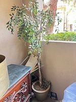 Full view of artificial tree in planter on patio corner