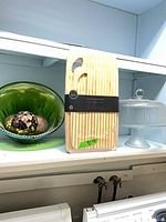Shelf view with green carnival bowl, sealed bamboo cutting board set, and glass cake stand with dome
