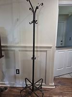 Full view of black metal coat rack showing hooks and base