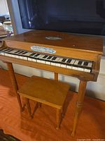 Front view of wooden toy piano and bench