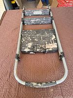 Ladder laid flat showing three plastic steps and metal frame