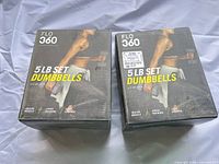Two FLO 360 5 lb set dumbbell boxes on cloth backdrop