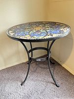 Full view of round mosaic table on wrought iron base