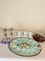 Full lot view showing deviled egg plate, heart plate, three egg cups, acrylic grinders, and glass cloche with wood base