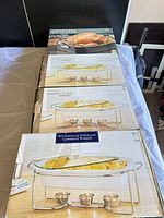 Stack of boxed casserole warmers and Oneida roasting pan