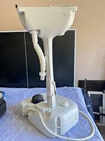 Full view of portable sink showing basin, column, water tank and hose