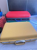 Front view of both suitcases closed, yellow in foreground, red/green in background
