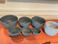 Front view of seven visible gray and white melamine mixing bowls, illustrating nesting sizes and pour spouts