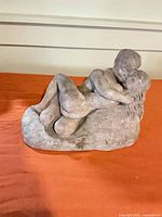 Front view of plaster sculpture showing embracing couple and matte gray finish