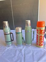 Four vacuum flasks standing side by side
