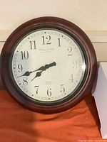 Front view of round Sterling & Noble wall clock showing dial and wood frame